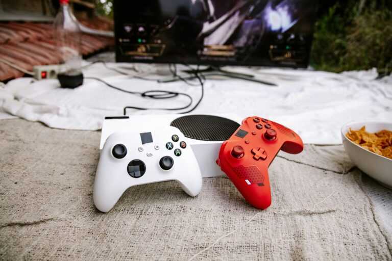 A gaming console with red and white controllers set up outdoors with a television screen.